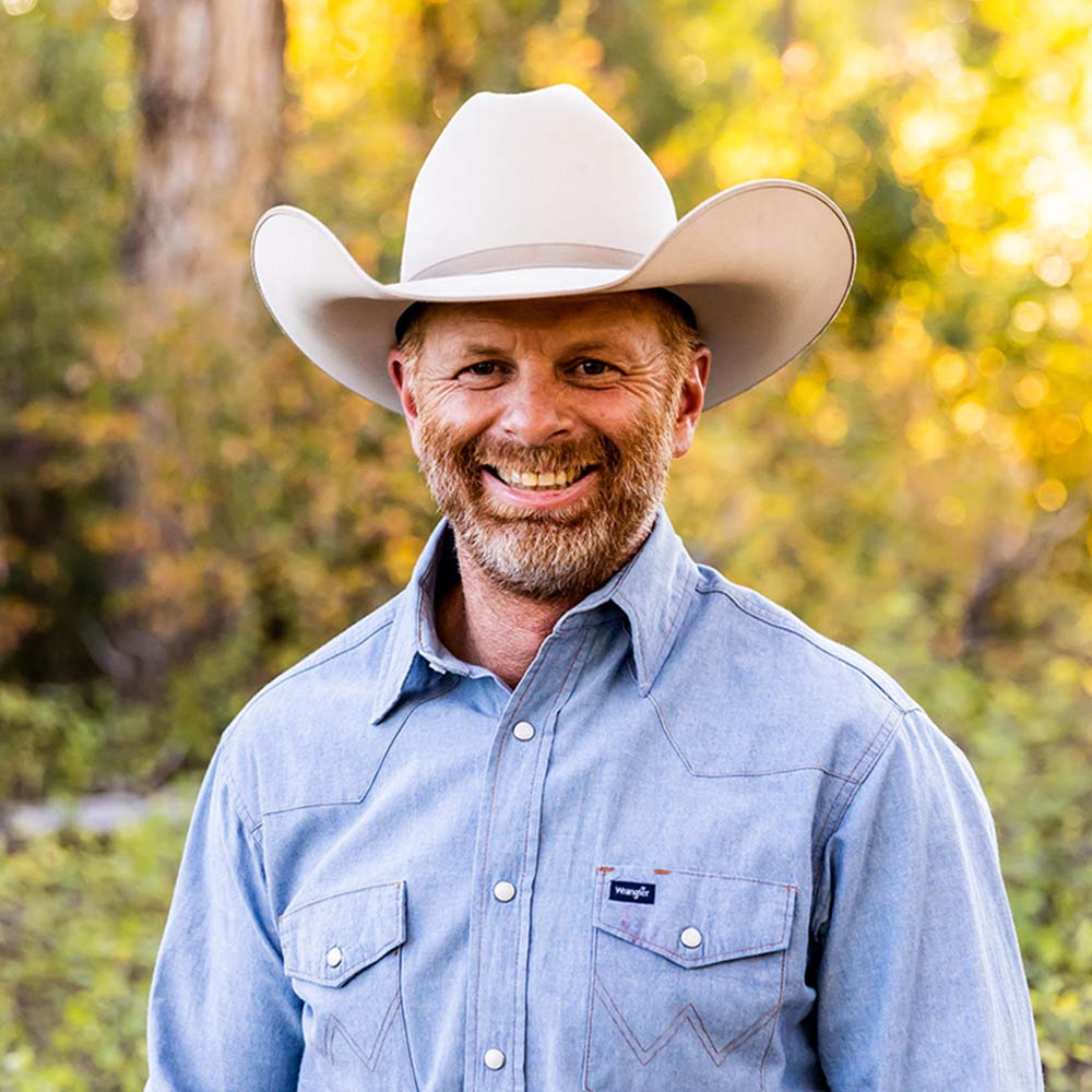 owner of High West Project Management Zac Davis is a button up shirt and cowboy hat smiling